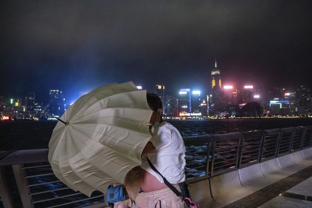 People hold an umbrella under strong wind on the promenade of Victoria Habour as tropical cyclone Ma-on approaches Hong Kong, Wednesday, August 24, 2022.Tropical Storm Ma-on was gaining strength as it headed for Hong Kong and other parts of southeastern China on Wednesday after displacing thousands in the Philippines. (Photo by Anthony Kwan/AP Photo)