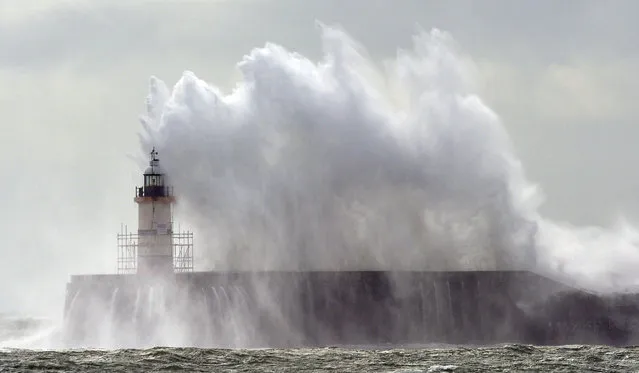 Waves crash into the harbour wall and over the lighthouse at Newhaven on the south coast of England on September 14, 2015 during high winds. (Photo by Glyn Kirk/AFP Photo)