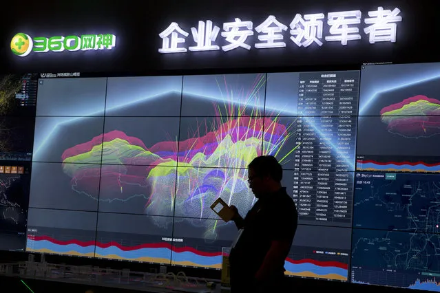 A worker is silhouetted against a computer display showing a live visualization of the online phishing and fraudulent phone calls across China during the 4th China Internet Security Conference (ISC) in Beijing, Tuesday, August 16, 2016. Despite China's tight controls on the flow of information on the internet, online fraud and identity theft are posing major challenges to authorities as e-commerce and other online services boom. Chinese characters at top reads “Enterprise Safety Leader”. (Photo by Ng Han Guan/AP Photo)