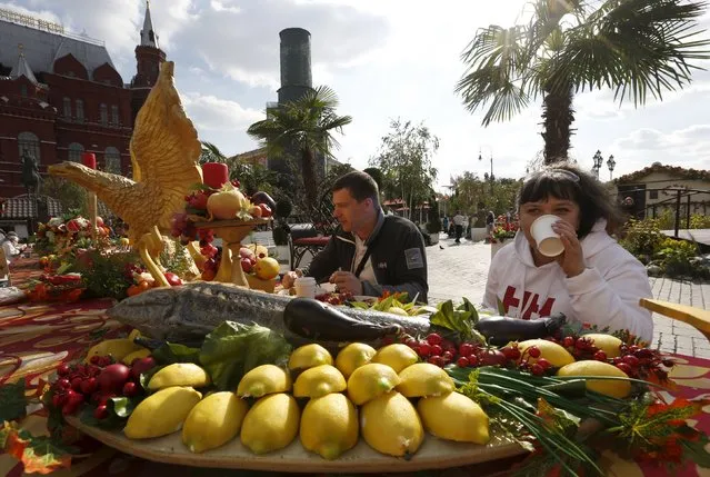 People have a meal while sitting at table with food models as the gastronomic festival "Moscow autumn” takes place near the Kremlin (R) and the State Historical Museum (L) in central Moscow, Russia, September 16, 2015. (Photo by Sergei Karpukhin/Reuters)