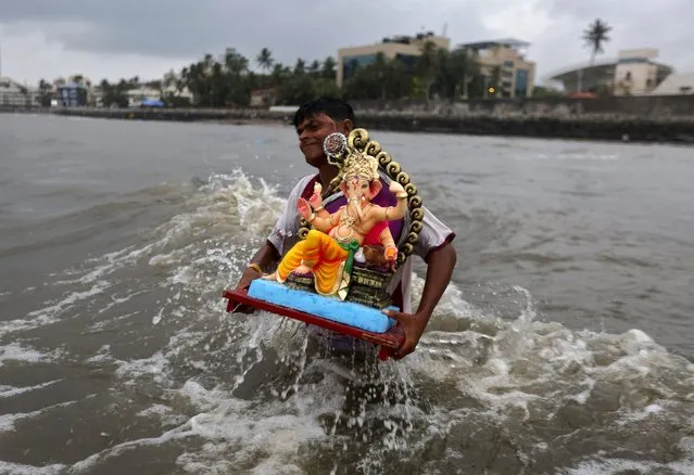A devotee carries an idol of the Hindu elephant god Ganesh, the deity of prosperity, for its immersion into the Arabian Sea during the ten-day-long Ganesh Chaturthi festival in Mumbai, India, September 18, 2015. (Photo by Shailesh Andrade/Reuters)