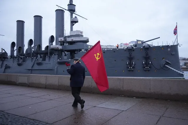A Communist party supporter walks past the Aurora Cruiser in the day of the 105th anniversary of the 1917 Bolshevik revolution in St. Petersburg, Russia, Monday, November 7, 2022. In October 1917 crew members on the Aurora used the front deck gun to fire a blank shot giving the signal to leftist fighters to storm the Winter Palace and to begin the Bolshevik Revolution. (Photo by Dmitri Lovetsky/AP Photo)