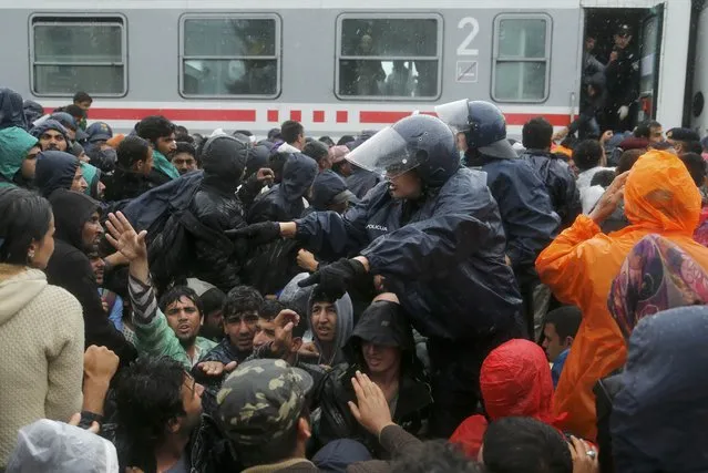 Police talks to migrants in the rain, waiting to board a train at the station in Tovarnik, Croatia, September 20, 2015. (Photo by Antonio Bronic/Reuters)