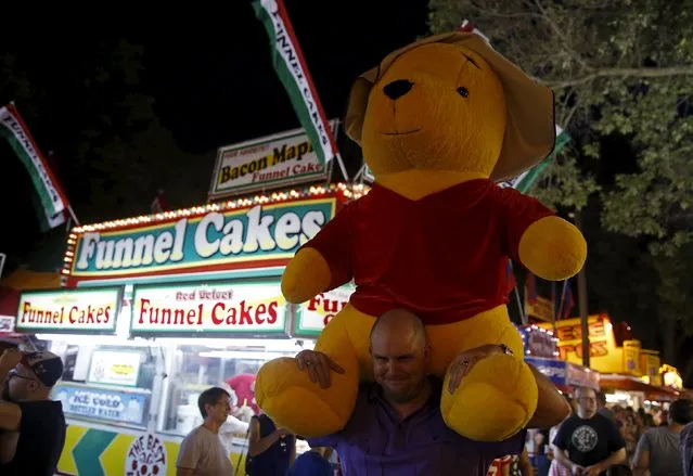 A man carries an oversized stuffed toy on his shoulders at the Iowa State Fair in Des Moines, Iowa, United States, August 15, 2015. (Photo by Jim Young/Reuters)