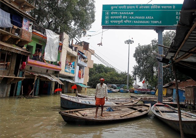 A man stands on a boat in front of partially submerged houses along a street flooded by water from the banks of the river Ganga, in Allahabad, India, August 26, 2016. (Photo by Jitendra Prakash/Reuters)