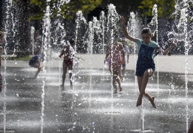 Children cool off in a public fountain in Vilnius, Lithuania, Friday, July 17, 2020. An heat wave has been hitting Lithuania with temperatures up high at 27 degrees Celsius (80.6 degrees Fahrenheit). (Photo by Mindaugas Kulbis/AP Photo)