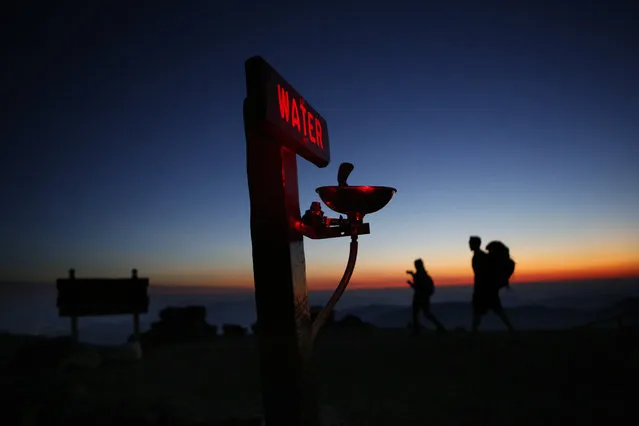 Quincy Andrews, left, and Josh Fournier, both of Meredith, N.H., arrive at dawn on September 24, 2017, at the summit of Mount Washington, N.H., where a water fountain awaits visitors to New England's highest peak. The weather observatory on the summit recorded a record daily temperature high when the mercury hit 65 degrees that day. (Photo by Robert F. Bukaty/AP Photo)