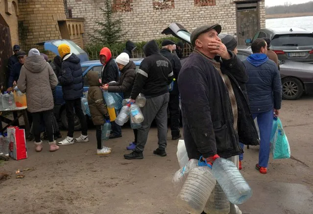 People fill up bottles with water near Dnipro river after Russia's military retreat from Kherson, Ukraine on November 29, 2022. (Photo by Anna Voitenko/Reuters)