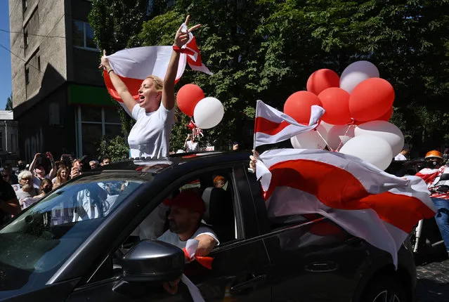 A woman waves a variant flag of Belarus as she rides in a car by Kiev's streets, in support of Belarus people protesting vote rigging in the presidential election on August 16, 2020. Belarusian President Alexander Lukashenko rejected calls for a new vote and urged supporters to “defend your country” on August 16 as tens of thousands gathered for what opponents hope will be the biggest demonstration yet against his disputed re-election. (Photo by Sergei Supinsky/AFP Photo)