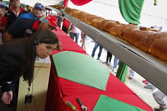 Kim Partrick (L), a representative of the Guinness World Records, examines a giant ham bread, a typical Venezuelan Christmas dish, during an attempt to break the Guinness World Record for the biggest ham bread, in Caracas November 15, 2014. (Photo by Carlos Garcia Rawlins/Reuters)