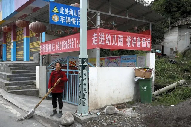 A woman sweeps outside a kindergarten school displaying a banner which reads: “Please speak Mandarin when you enter the school” at a village in Ganluo county, southwest China's Sichuan province on September 10, 2020. (Photo by Andy Wong/AP Photo)