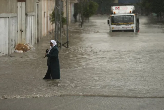 A Palestinian journalist speaks to the camera as she stands on a flooded street following heavy rain in Gaza City November 27, 2014. The civil defence asked residents in an area east of Gaza City to evacuate their homes to avoid being trapped in flood waters from a nearby lake. (Photo by Mohammed Salem/Reuters)