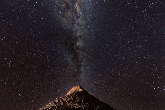 The Milky Way appears over a mountain in the Valle de la Luna in the Atacama Desert, considered the driest place on earth on August 26, 2022 near San Pedro de Atacama, Chile. The extreme aridity makes the Atacama Desert one of the clearest places on earth to view the night sky. Much of the region receives less than half an inch of rainfall per year, and some areas none at all for hundreds of years. Located in Chile's northern third between two mountain ranges, the Atacama is possibly the oldest desert on earth, experiencing extreme aridity for at least 3 million years. The area is home to the Atacama Large Millimeter/submillimeter Array (ALMA) telescope. The Valley of the Moon is so called because of its lunar and even Mars-like appearance. (Photo by John Moore/Getty Images,)
