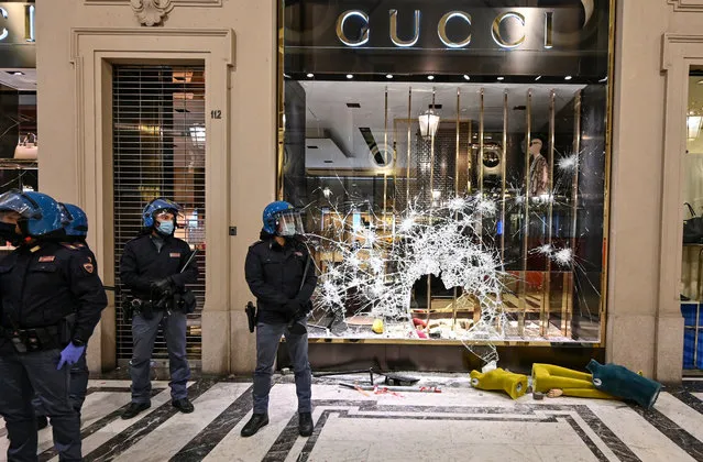 Police officers stand guard outside a Gucci boutique store as protesters gather during an anti government demonstration on October 26, 2020 in Turin, Italy. Following a surge in new COVID-19 cases, demonstrators have taken to the streets to protest against Italy's new restrictions, which includes the 6pm closure of bars and restaurants, the complete closure of most outdoor sporting and entertainment facilities and a total ban on fans in soccer stadiums. (Photo by Diego Puletto/Getty Images)