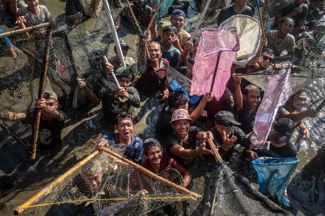 People wait with nets to catch about 2 tonnes of fish released for free by municipal workers during Memed Ikan, an annual traditional fish-catching festival held to give thanks to God for the abundance of fish harvests, at the Gemblegan Reservoir in Klaten, Central Java, on July 20, 2025. (Photo by Devi Rahman/AFP Photo)