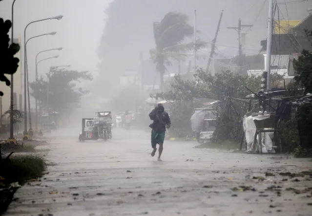 A man walks on a street while strong winds and heavy rain, brought by typhoon Hagupit, batter Atimonan town, Quezon province, south of Manila December 8, 2014. (Photo by Romeo Ranoco/Reuters)