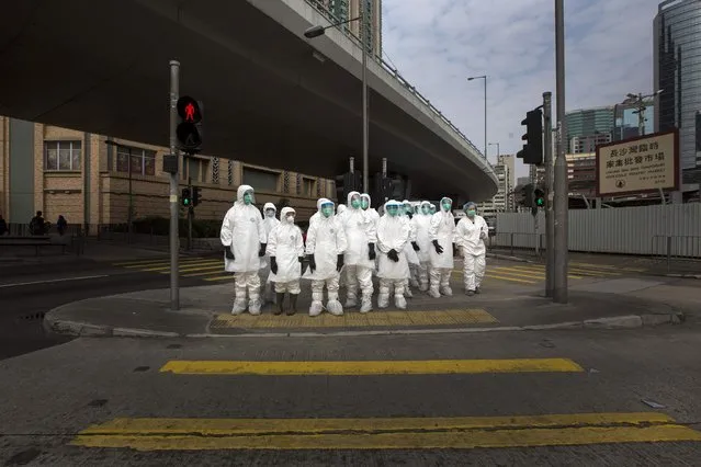 Health officers in full protective gear wait to cross a road near a wholesale poultry market in Hong Kong, in this January 28, 2014 file photo. (Photo by Tyrone Siu/Reuters)