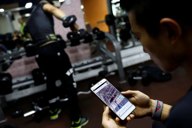 Fitness trainer Bi Zhenbo looks at a video of a high bar routine by Shi Shenwei at a gym in Beijing, China, October 5, 2016. “I think this person gives a lot of inspiration to us. And I think he’s really amazing. He inspires more and more young people to do what they like, like working out. I think he’s doing something very meaningful”, Bi said about Shi Shenwei. (Photo by Thomas Peter/Reuters)