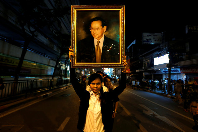 A woman poses with a portrait of Thailand's King Bhumibol Adulyadej, as others line up to hold the portrait, after the announcement of the king's death, outside Siriraj hospital in Bangkok, Thailand October 13, 2016. (Photo by Jorge Silva/Reuters)