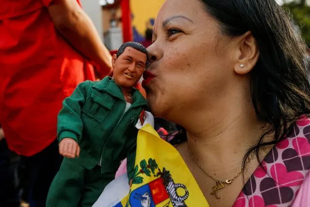 A government supporter kisses a toy depicting late Venezuelan President Hugo Chavez during the celebration of the 21st anniversary of late President Hugo Chavez's return to power after a failed coup attempt in 2002, in Caracas, Venezuela on April 13, 2023. (Photo by Leonardo Fernandez Viloria/Reuters)