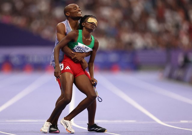 Namibia's Lahja Ishitile (R) is embraced by her guide Sem Shimanda (L) after winning the Women's 400m T11 Final at the Paris 2024 Paralympic Games, in the Stade de France, Saint-Denis, north of Paris on August 31, 2024. (Photo by Franck Fife/AFP Photo)