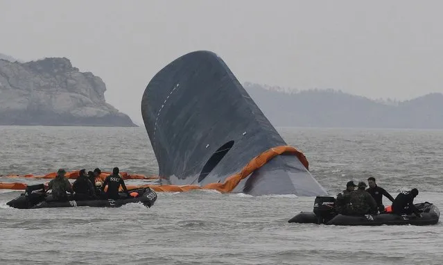 In this April 17, 2014 file photo, South Korean Coast Guard personnel search for missing passengers aboard the sunken ferry Sewol in the waters off Jindo, South Korea. (Photo by Ahn Young-joon/AP Photo)