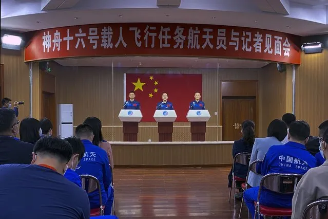 Chinese astronauts for the upcoming Shenzhou-16 mission from left, Gui Haichao, Jing Haipeng and Zhu Yangzhu are seen behind glass during a meeting of the press at the Jiuquan Satellite Launch Center in northwest China on Monday, May 29, 2023. China's space program plans to land astronauts on the moon before 2030, a top official with the country's space program said Monday. (Photo by Mark Schiefelbein/AP Photo)