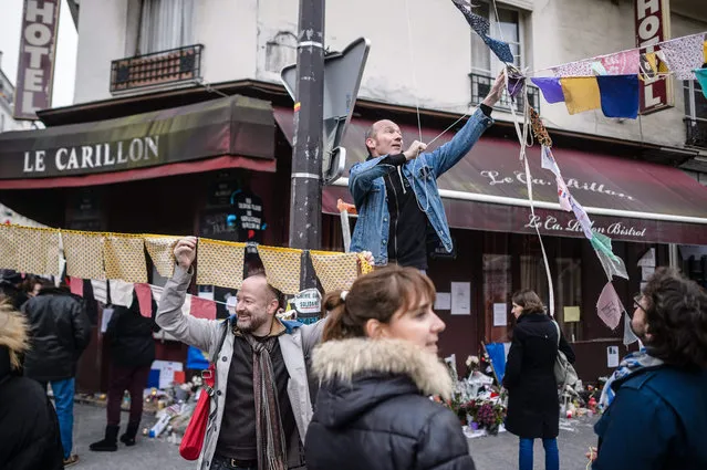 One month after the Paris attacks, local residents of Carillon cafe and Petit Cambodge restaurant adorn the street with colorful flags, in Paris, France, 13 December 2015. 130 people were killed and hundreds injured in the terror attacks which targeted the Bataclan concert hall, the Stade de France national sports stadium, and several restaurants and bars in the French capital on 13 November 2015. (Photo by Christophe Petit Tesson/EPA)