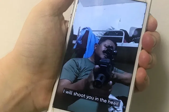 A mobile phone shows a picture of a Myanmar man in an army shirt threatening to shoot anti-coup protesters. Photo taken in Singapore on March 4, 2021. (Photo by Fanny Potkin/Reuters)