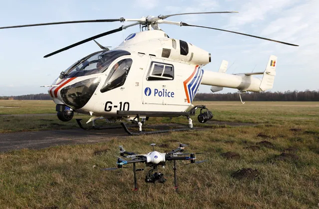 A Belgian Federal Police drone is seen in front of a helicopter on the airfield in Brasschaat, near Antwerp, Belgium, December 23, 2015. The first drone to be used by Belgian Federal Police can fly with 135 km/h, up to 2km high and will be deployed to watch over crime scenes, respond to threats, and look for missing people, according to Belgian Federal Police. (Photo by Francois Lenoir/Reuters)
