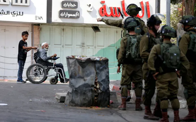 A wheelchair-bound Palestinian man is pushed during clashes between Palestinians and Israeli troops in Hebron in the occupied West Bank, August 3, 2018. (Photo by Mussa Qawasma/Reuters)