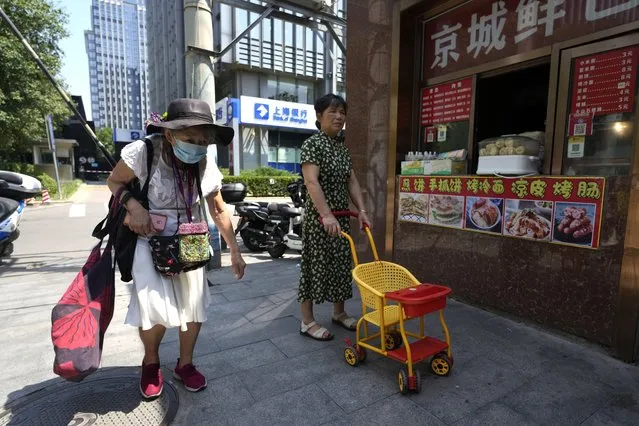 An elderly woman walks by a store selling snacks in Beijing, Monday, July 17, 2023. (Photo by Ng Han Guan/AP Photo)