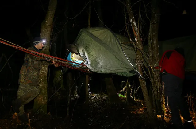 Belarussian tourists prepare to sleep in a tent installed on the trees as they take part in “Search and rescue operations – 2016”, a three-day competition, near the village of Priselki, Belarus, November 25, 2016. Photo taken November 25, 2016. (Photo by Vasily Fedosenko/Reuters)