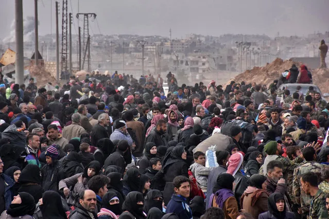 Syrian families, fleeing from various eastern districts of Aleppo, queue to get onto governmental buses on November 29, 2016 in the government-held eastern neighbourhood of Jabal Badro, before heading to government-controlled western Aleppo, as the Syrian government offensive to recapture rebel-held Aleppo has prompted an exodus of civilians. The Syrian government offensive to recapture rebel-held Aleppo sparked international alarm, with the UN saying nearly 16,000 people had fled the assault and more could follow. The fighting has prompted an exodus of terrified civilians, many fleeing empty-handed into remaining rebel-held territory, or crossing into government-controlled western Aleppo or Kurdish districts. (Photo by George Ourfalian/AFP Photo)