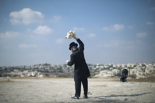 An Ultra-Orthodox Jewish man swings a chicken over his head as part of the Kaparot ritual in Beit Shemesh, Israel, Monday, September 17, 2018. Observant Jews believe the ritual transfers one's sins from the past year into the chicken, and is performed before the Day of Atonement, Yom Kippur, the holiest day in the Jewish year which starts at sundown Tuesday. (Photo by Oded Balilty/AP Photo)