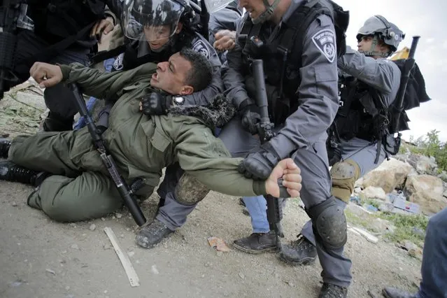 Israeli border policemen detain a Palestinian man as they clear a protest on land that Palestinians say was confiscated by Israel for Jewish settlements, near the West Bank town of Abu Dis near Jerusalem February 16, 2015. (Photo by Ammar Awad/Reuters)