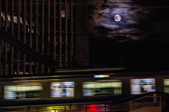 The moon rises as a train passes by Wednesday, April 28, 2021, in Tokyo. (Photo by Kiichiro Sato/AP Photo)