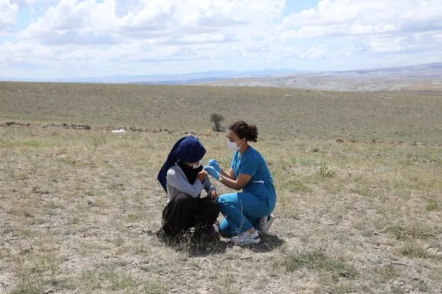 A health worker vaccinates a farm worker in the village of Oguzlar, a hundred of kilometres away from Ankara on July 8, 2021. Health workers affiliated to the Ministry of Health administered Pfizer Biontech and Sinovac vaccine against COVID-19 to seasonal agricultural workers in their villages. (Photo by Adem Altan/AFP Photo)