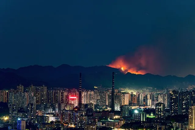 Smoke and flames rise into the sky during a mountain forest fire triggered by persistent drought and heat waves on August 21, 2022 in Chongqing, China. The fire erupted on Sunday evening in Chongqing's Banan district, while no casualties have been reported so far. (Photo by VCG/VCG via Getty Images)