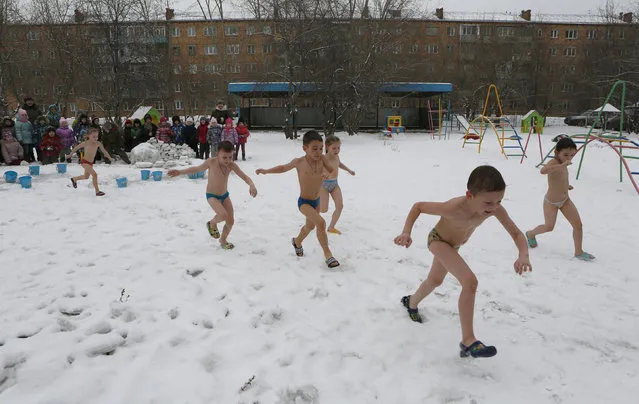 Children watch their classmates run barefoot on snow after pouring cold water on themselves, under the watch of fitness coach Oksana Kabotko (not pictured), as part of a health and fitness program at a local kindergarten in subzero temperatures, in Krasnoyarsk, Siberia, Russia, February 9, 2016. (Photo by Ilya Naymushin/Reuters)
