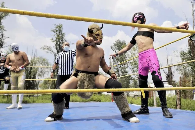 Minos (center) and Sol (right), professional wrestlers, before a wrestling match where they go head to head with other gladiators in a ring at the Embarcadero Puente de Urrutia in Xochimilco, Mexico City on July 28, 2021, in order to generate income to survive during the COVID-19 health emergency and the orange epidemiological traffic light in the capital. (Photo by Gerardo Vieyra/NurPhoto via Getty Images)