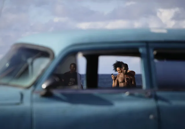 People use their mobile phones on Havana's seafront boulevard El Malecon, April 2012. (Photo by Desmond Boylan/Reuters)