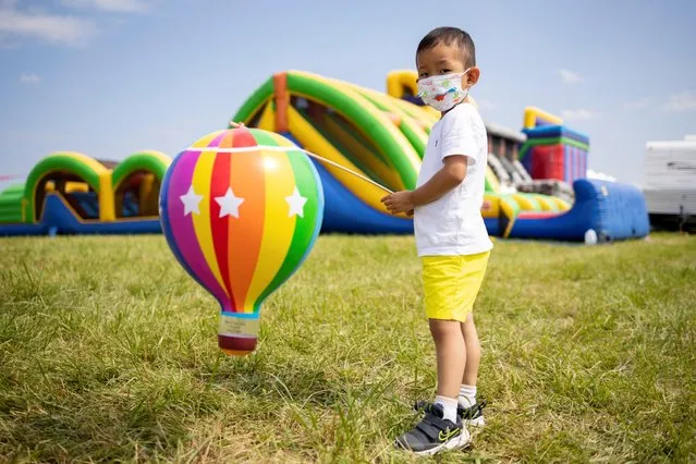 A boy plays with a toy hot air balloon during the New Jersey Lottery Festival of Ballooning in Readington, New Jersey, U.S., July 24, 2021. (Photo by Hannah Beier/Reuters)
