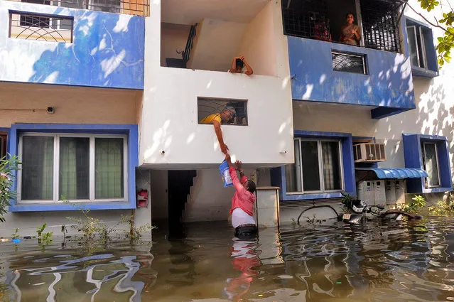 A volunteer offers food to a resident after his house got partially submerged following heavy rains due to Cyclone Michaung, in Chennai, India on December 6, 2023. (Photo by Reuters/Stringer)