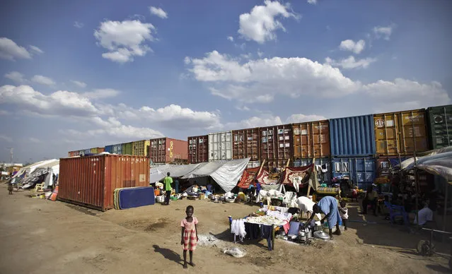 A displaced child stands in front of the makeshift tents where she and others live next to shipping containers at a United Nations compound which has become home to thousands of people displaced by the recent fighting, in the capital Juba, South Sudan Sunday, December 29, 2013. (Photo by Ben Curtis/AP Photo)