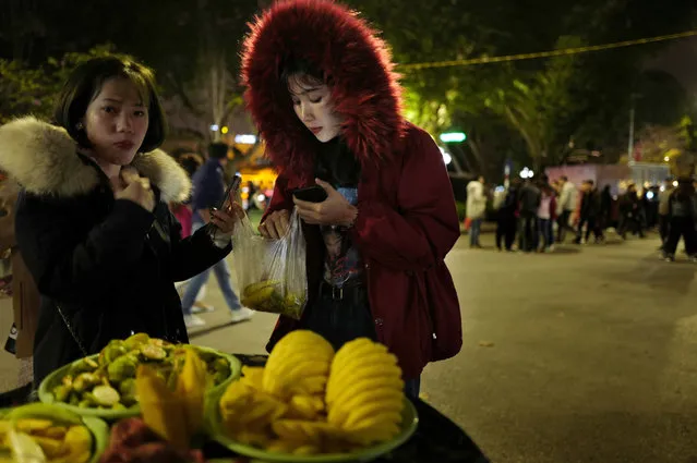 In this Saturday, February 23, 2019, photo, women buy fruits at a booth near Hoan Kiem Lake in Hanoi, Vietnam. (Photo by Vincent Yu/AP Photo)