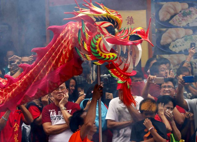 People react to the smoke of exploding firecrackers as dragon and lion dancers perform during the Chinese Lunar New Year celebrations, Saturday, January 28, 2017, in the Chinatown area of Manila, Philippines. (Photo by Bullit Marquez/AP Photo)