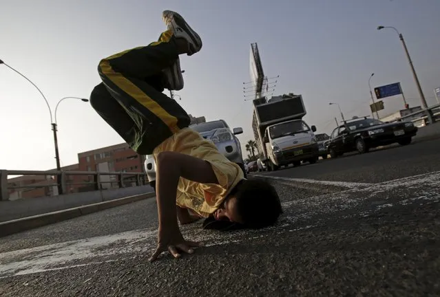 A boy somersaults at a traffic junction in Lima April 27, 2015. (Photo by Mariana Bazo/Reuters)
