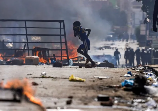 A boy runs past barricades as Senegalese demonstrators clash with riot police during a protest against the postponement of the presidential election, in Dakar, Senegal on February 4, 2024. (Photo by Zohra Bensemra/Reuters)
