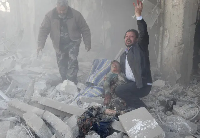 A Syrian man reacts as he carries the body of a child following a reported air strike by government forces on the al-Haidarya neighbourhood in the northern city of Aleppo on February 12, 2014. More than 136,000 people have been killed in Syria's nearly three-year war, and millions more forced to flee their homes. (Photo by Khaled Khatib/AFP Photo/Aleppo Media Centre)